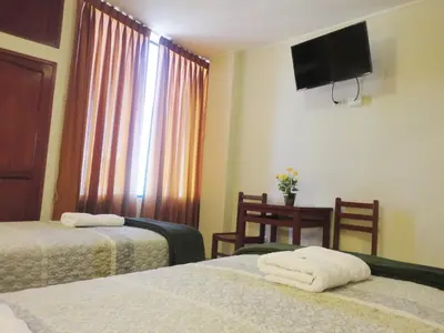 a hotel room with two beds and a television on the wall at Hotel Torontel in Ica