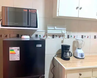 a microwave on top of a refrigerator in a kitchen at Pershing lindo dpto amoblado 2dorm y wifi in Lima