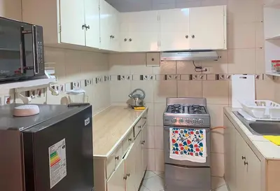 a small kitchen with a stove and a microwave at Pershing lindo dpto amoblado 2dorm y wifi in Lima