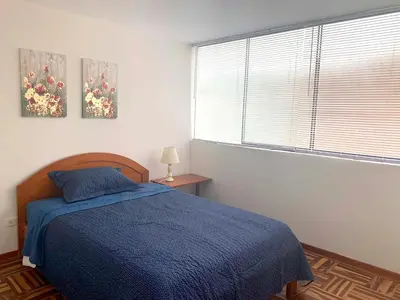 a bedroom with a blue bed and a window at Pershing lindo dpto amoblado 2dorm y wifi in Lima