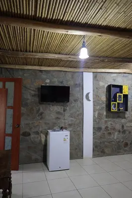 a room with a refrigerator and a tv on a stone wall at Cha'skas Checkta Eco-Lodge in Santa Rosa de Quives