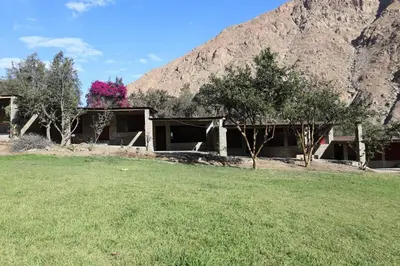 a house with a field in front of a mountain at Cha'skas Checkta Eco-Lodge in Santa Rosa de Quives