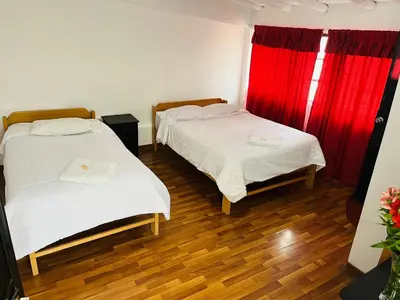 two beds in a room with red curtains at ENEDE HOSTEL in Cusco