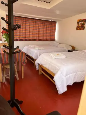 a hotel room with two beds and a table and chairs at ENEDE HOSTEL in Cusco
