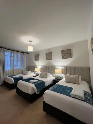 a hotel room with three beds and two lamps at Katari at Plaza de Armas Cusco in Cusco
