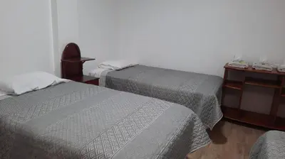a bedroom with two beds and a table with a night stand at Hospedaje Margarita in La Merced