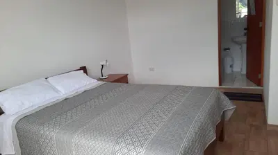 a bedroom with a bed and a bathroom with a toilet at Hospedaje Margarita in La Merced