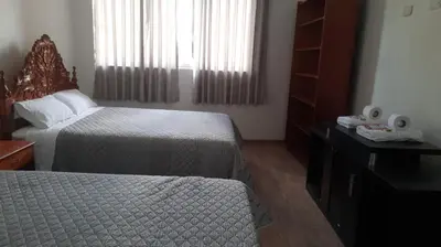 a hotel room with two beds and a window at Hospedaje Margarita in La Merced