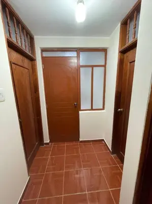 a hallway with wooden doors and a tile floor at Departamento D&C I entero acogedor in Huancayo