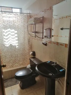a bathroom with a black toilet and a sink at Departamento D&C I entero acogedor in Huancayo