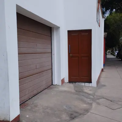 a garage with a brown door and a sidewalk at Barranco monumental in Lima
