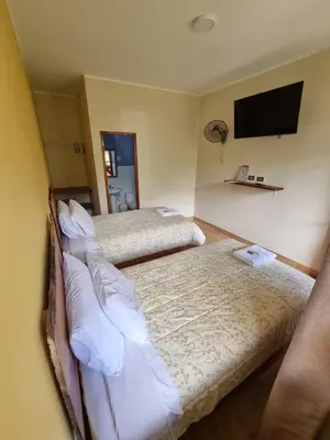 a hotel room with two beds and a flat screen tv at Pampa Bella Lodge in La Merced