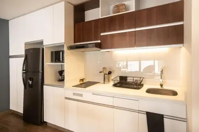 a kitchen with white cabinets and a black refrigerator at SoHo by Wynwood House in Lima