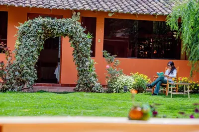 a woman sitting on a chair in front of a house at LILIUM VALLEY in Ollantaytambo