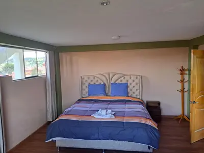 a bedroom with a large bed with blue pillows at Maychu's Albergue in Chinchero