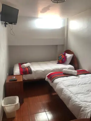 a room with two beds and a television in it at Hotel TIKA AYNA Cerca a la plaza de Armas CUSCO in Cusco