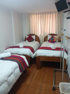 a room with two twin beds and a tv at Hotel TIKA AYNA Cerca a la plaza de Armas CUSCO in Cusco