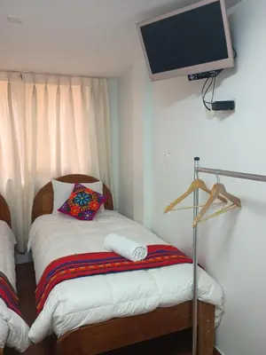 a bedroom with a bed with a tv on the wall at Hotel TIKA AYNA Cerca a la plaza de Armas CUSCO in Cusco