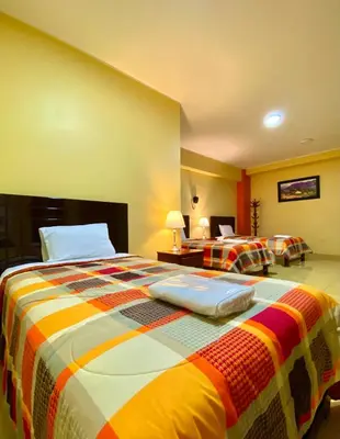 a bedroom with a large bed with a colorful blanket at Hotel Las Palmeras in Huacho