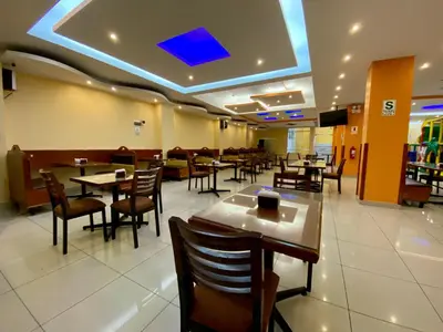 a dining room with tables and chairs in a restaurant at Hotel Las Palmeras in Huacho