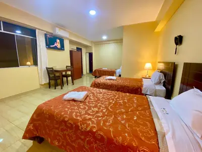 a hotel room with two beds and a table at Hotel Las Palmeras in Huacho
