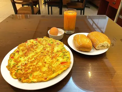 a table with two plates of omelet and bread and orange juice at Hotel Las Palmeras in Huacho