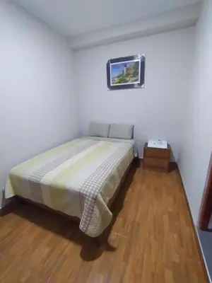 a bedroom with a bed in a white room at Hostal Pacífico Huánuco in Huánuco