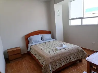 a small bedroom with a bed with a window at Hostal Pacífico Huánuco in Huánuco