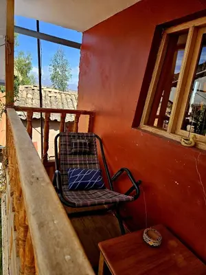 a chair on a balcony with a table and a window at KanchayKillaWasi in Chinchero