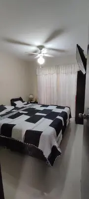 a bedroom with a black and white bed with a ceiling fan at Casa Club Vacacional in Ica