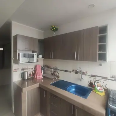 a kitchen with wooden cabinets and a blue sink at Depawanka 1 departamento amoblado in Huancayo