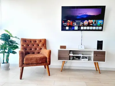a room with a chair and a tv on a wall at Stylish New Apartment with stunning Ocean View near Miraflores in Lima