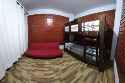 a room with bunk beds with a red couch at CASA PLAYA REFUGIO AZUL in Cerro Azul