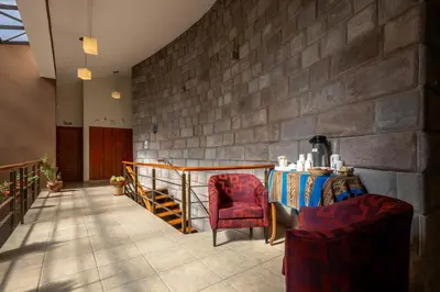 a lobby with two chairs and a table and a stone wall at Mamasara Cusco in Cusco