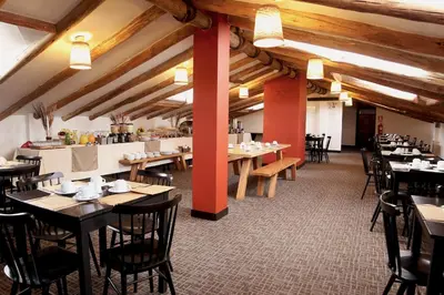 a restaurant with tables and chairs in a room with wooden ceilings at Abittare Hotel in Cusco
