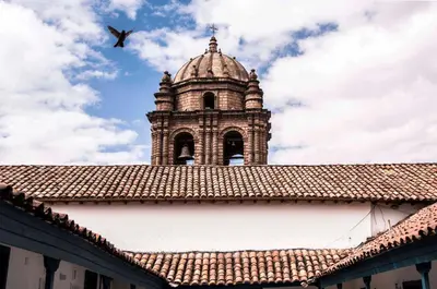 a bird flying over a building with a tower at Abittare Hotel in Cusco