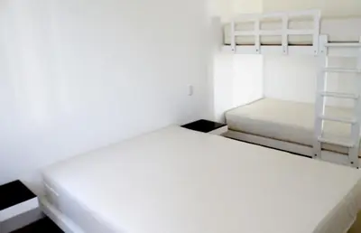 two beds in a white room with two bunk beds at Casa 33 Sotavento Paracas in Paracas
