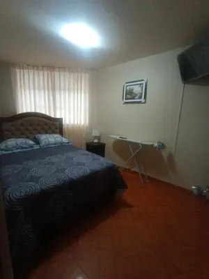 a bedroom with a bed and a table in it at LUANA’S HOUSE in Ica