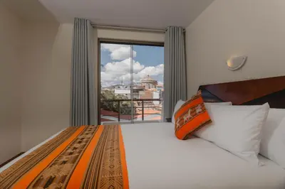 a bedroom with a bed and a large window at Quechua ApartHotel in Cusco