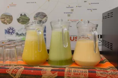 three glass containers of orange and green juice on a table at Quechua ApartHotel in Cusco