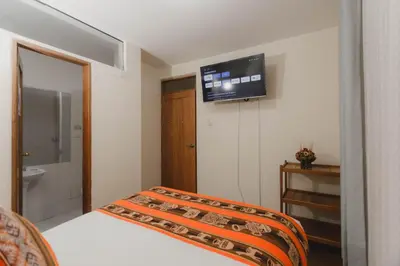a bedroom with a bed and a television on the wall at Quechua ApartHotel in Cusco