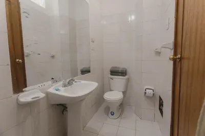a white bathroom with a toilet and a sink at Quechua ApartHotel in Cusco