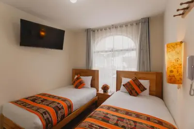 two beds in a room with a window at Quechua ApartHotel in Cusco