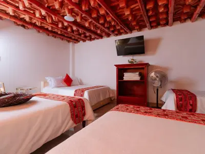 a bedroom with two beds and a tv on the wall at Hotel Viñas del Sol Eterno in Chincha Alta