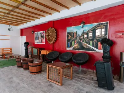 a room with a red wall with chairs and tables at Hotel Viñas del Sol Eterno in Chincha Alta