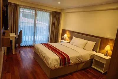 a hotel room with a bed and a desk and a window at Tikawasi ollanta 2 incluye transporte o recojo a la estacion de tren in Ollantaytambo