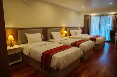 two beds in a hotel room with two lamps at Tikawasi ollanta 2 incluye transporte o recojo a la estacion de tren in Ollantaytambo