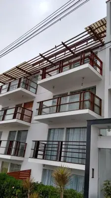 a white apartment building with windows and a palm tree at Minidepartamento en San Bartolo - VISTA AL MAR in San Bartolo