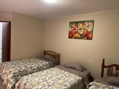 a bedroom with two beds and a painting of fruit at Entre Cava y Cata in Ica