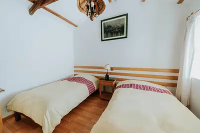 two beds in a room with a table and a window at Hotel Vallehermoso in Cotahuasi